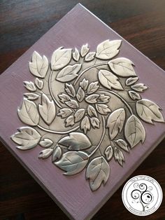 a close up of a wooden block with leaves and flowers on it, sitting on a table