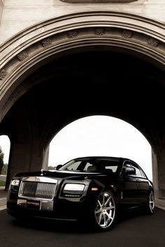 a black rolls royce parked under an arch