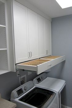 a washer and dryer in a small room with white cupboards on the wall