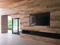 an empty room with a flat screen tv on the wall and sliding glass doors leading outside