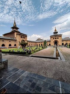 a large building with a fountain in front of it and people walking around the courtyard