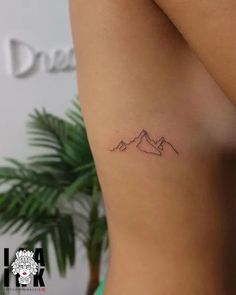 a small mountain tattoo on the back of a woman's left arm is shown