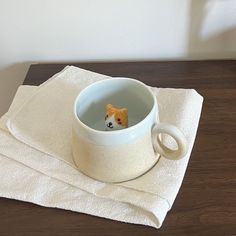 a small dog in a bowl on top of a table next to a white towel