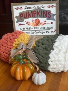 three pumpkins sitting on top of a wooden table next to a sign that says farmer's market pumpkins