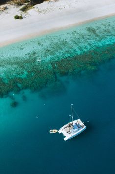 an aerial view of a boat in the water next to a sandy beach and coral reef