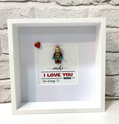 a lego minifigure in a white shadow box with i love you on it