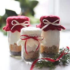 three jars filled with food sitting on top of a white table next to a red ribbon