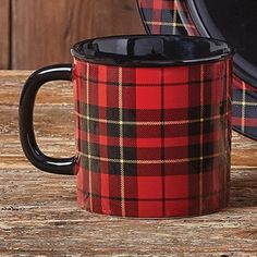 a black and red plaid coffee mug sitting on top of a wooden table