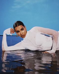 a woman in white laying on the water