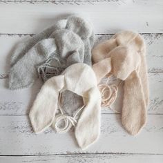 three sweaters and ties laid out on a white wooden surface, one has a knot in the middle