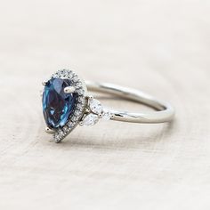 a blue and white diamond ring sitting on top of a table