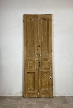 an old pair of wooden doors sitting on top of a hard wood floor next to a white wall