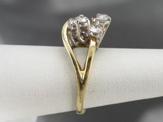 This diamond statement ring is like a modernist sculpture! Two loops interlock – one gleaming in warm yellow gold, the other set with a dazzling display of diamonds. With its high profile and asymmetrical design, this ring will turn heads! Metal: 14K Yellow and White Gold Gem: 11 Diamonds totaling 1.17 Carats, VVS in Clarity, G in Color Gem Measurements: 3.8 mm, Round (Largest) Ring Size: 5.75 Marks: "14K" Stamped on the inside band Modern Yellow Gold Bypass Ring With Brilliant Cut, Modern Twist Yellow Gold Diamond Ring For Formal Occasions, Gold Diamond Ring With Tension Setting And Modern Twist, Modern Twist Gold Diamond Ring For Anniversary, Gold Diamond Ring For Anniversary With Modern Twist, Modern Gold Diamond Ring With Brilliant Cut, Modern Twist Yellow Gold Diamond Ring For Anniversary, Anniversary Modern Twist Yellow Gold Diamond Ring, Anniversary Yellow Gold Diamond Ring With A Modern Twist