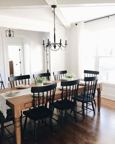 a dining room table with black chairs and a chandelier hanging from the ceiling