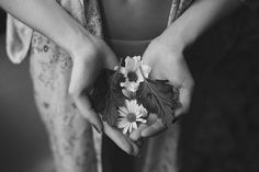 two hands holding flowers and leaves in black and white photo with text overlay that reads,