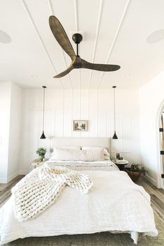 a bedroom with a white bed and ceiling fan