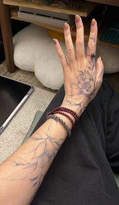 a woman's arm with flowers on it and a laptop in the back ground