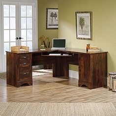 a computer desk with a laptop on top of it in front of a door and window