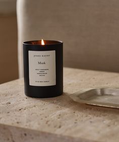 a black candle sitting on top of a table next to a silver tray with a spoon