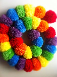 multicolored pom - poms arranged in a circle on a white surface