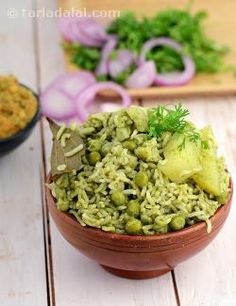 a bowl filled with rice and vegetables on top of a wooden table