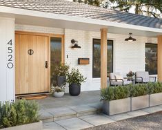 the front entrance to a home with potted plants and chairs on the patio area