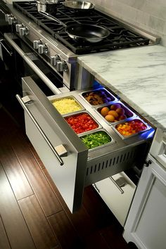 an open drawer in the middle of a kitchen counter with food items on it, including salads and condiments