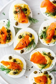 deviled eggs with smoked salmon, capers and olives on a white plate