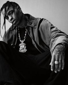 a black and white photo of a man with dreadlocks sitting on the floor