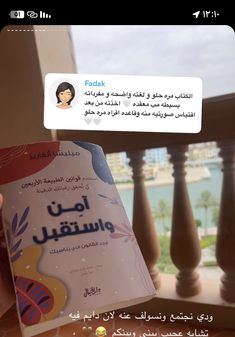 someone is holding up a book in front of a balcony with an arabic translation on it