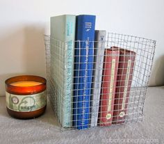 a wire basket holding books next to a candle