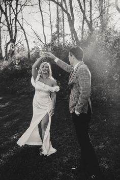 a man and woman dancing together in the grass with trees in the backgroud