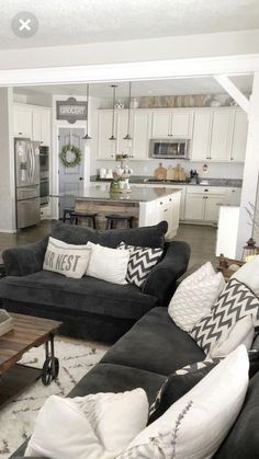 a living room filled with black couches and white pillows