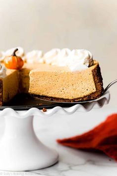 a slice of pumpkin cheesecake on a white cake platter with a red napkin