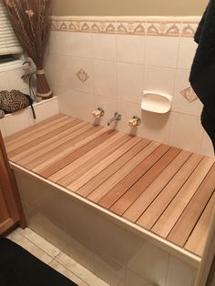 a wooden bench with two urinals on it in a bathroom next to a window