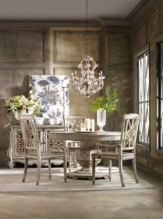 a dining room table with white chairs and a chandelier hanging from the ceiling