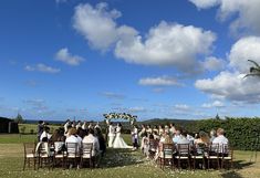 a group of people that are standing in front of a bunch of chairs on a grass field