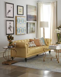 a living room filled with furniture and pictures hanging on the wall above it's windows