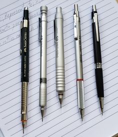 four pens lined up on top of a notebook