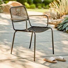 a pair of sandals sitting on the ground next to an empty chair and table outside