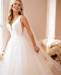 a woman in a wedding dress standing by a window