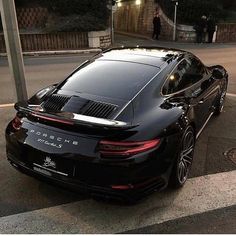 a black porsche is parked on the side of the road in front of a street light