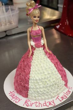 a barbie doll birthday cake with pink and white frosting on it's base