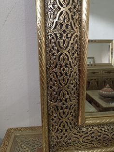 a gold framed mirror sitting on top of a table