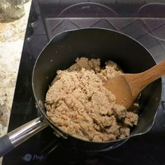 a wooden spoon in a pan filled with food on top of a stove burner