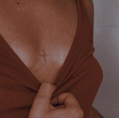 a woman with a tiny cross tattoo on her left side chest and right arm behind her back