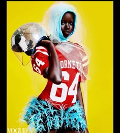 a woman wearing a football uniform and holding a silver helmet in front of a yellow background