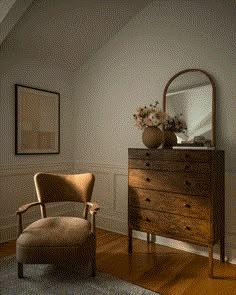 a room with a chair, dresser and mirror