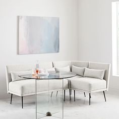 a glass table sitting on top of a white couch next to a gray sectional sofa