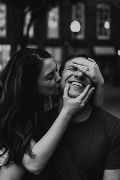 black and white photograph of a man kissing a woman's forehead in front of a building